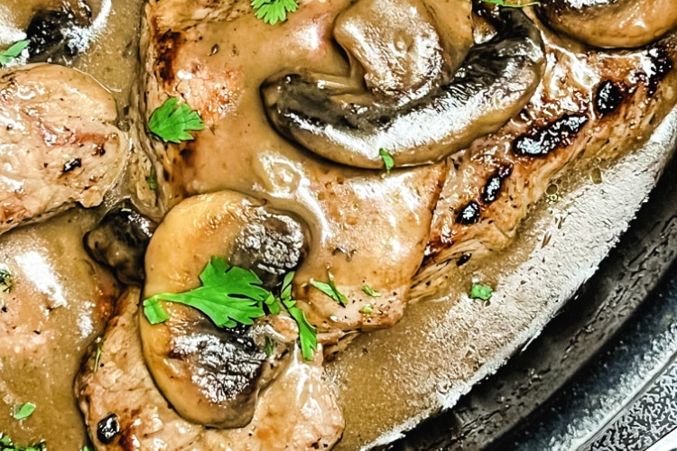 Sizzle Steaks nestled in Mushroom Gravy in a skillet.