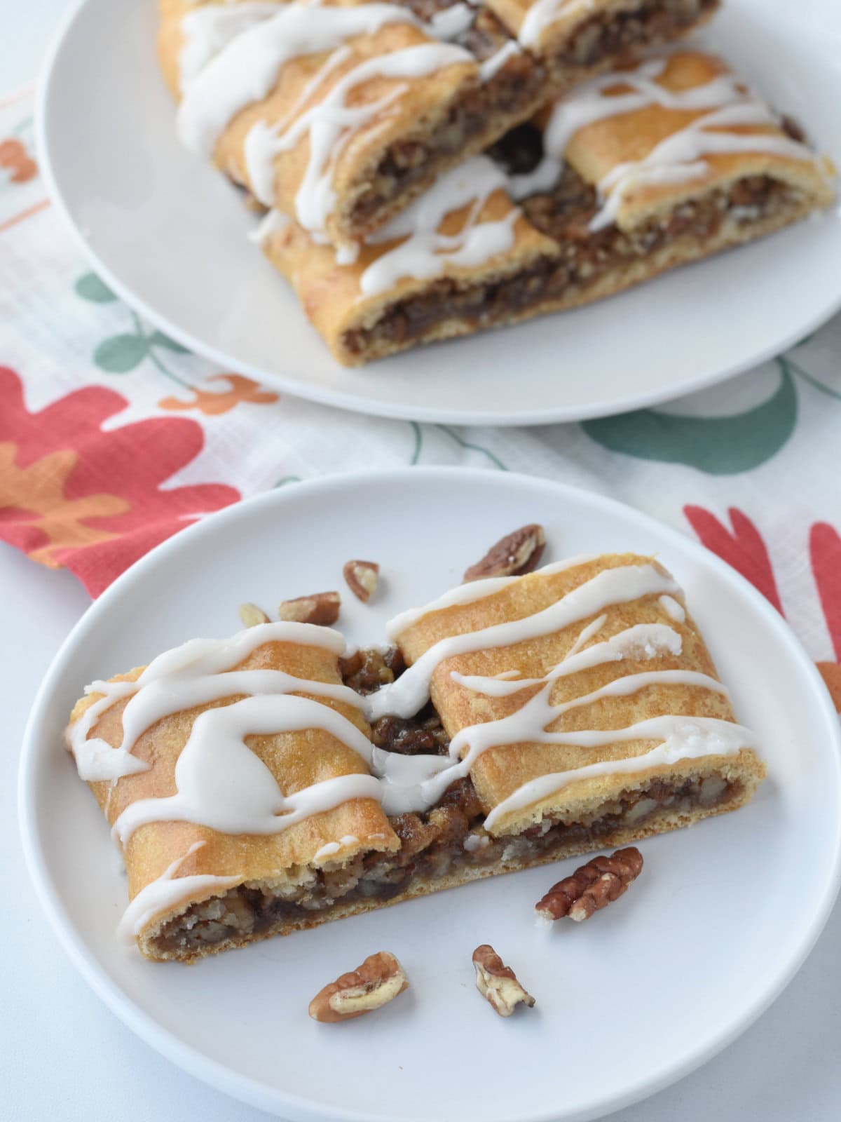 Kringle Crescent Roll Dough Desert on a white plate with two other pieces behind it. 