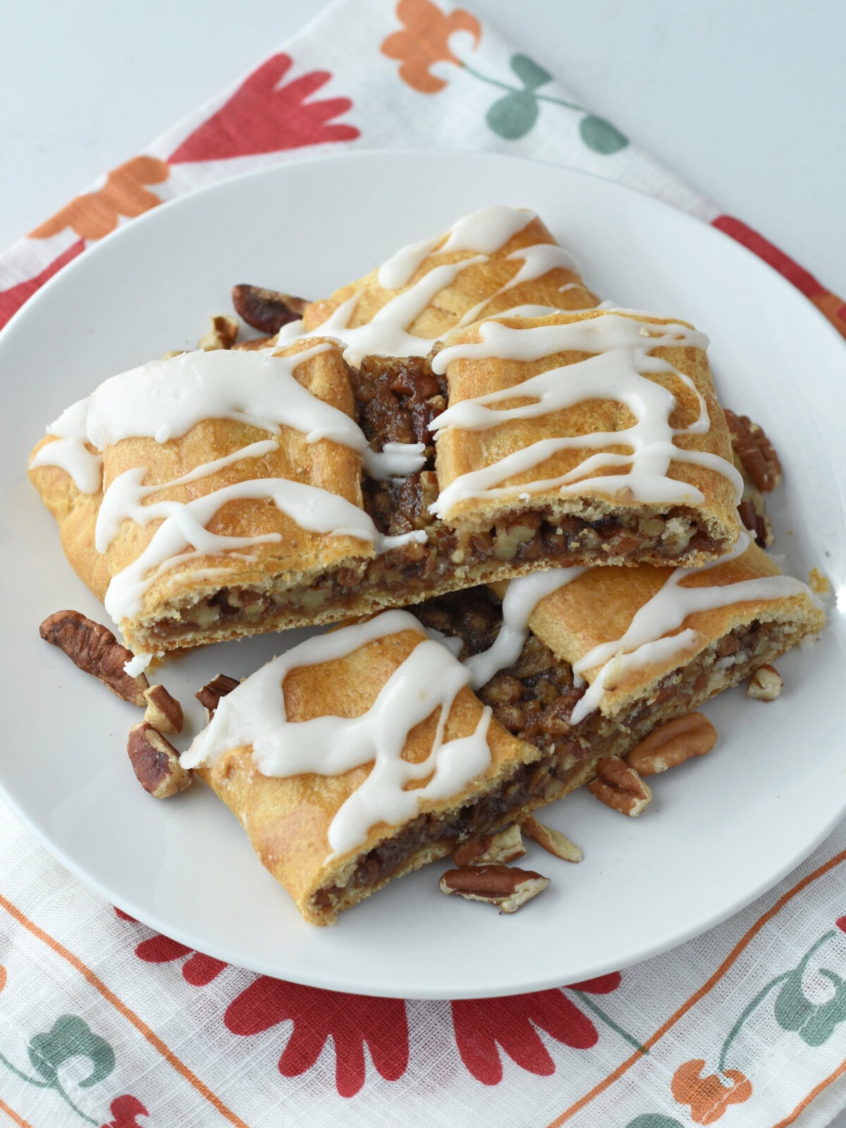 Kingle made with Crescent Rolls and pecans on a white plate with a napkin underneath. 
