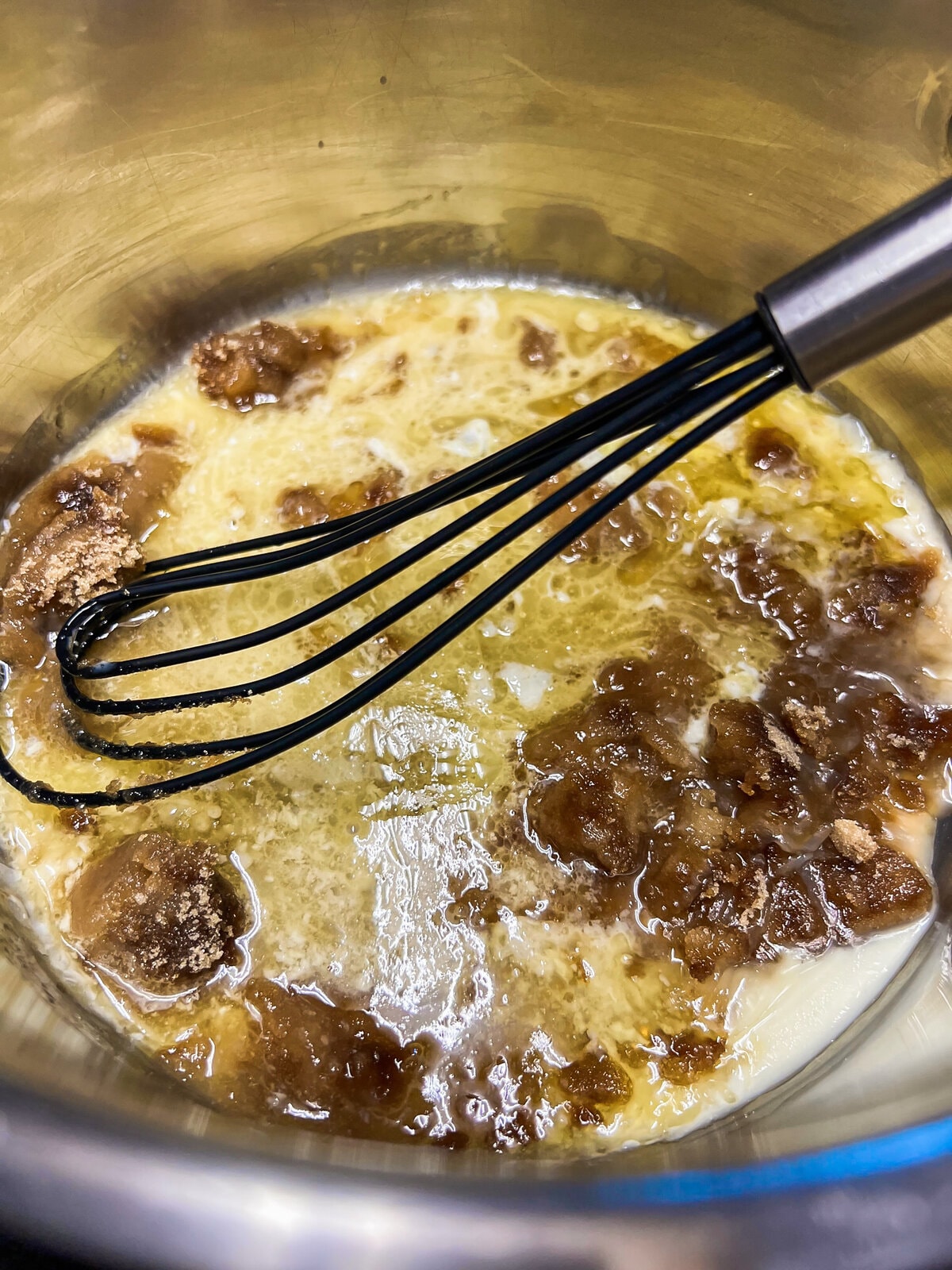 Sauce ingredients in a sauce pan with a whisk. 