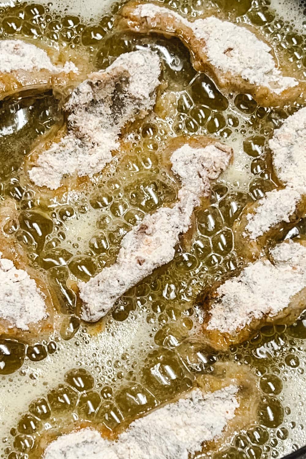 Chicken gizzards frying in hot oil until golden brown and crispy. 