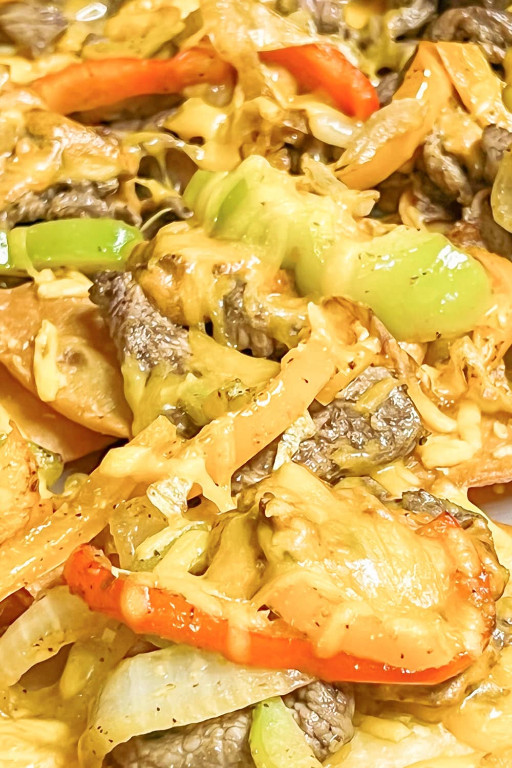 Sheet pan nachos with melted cheese, sizzle steak and peppers.