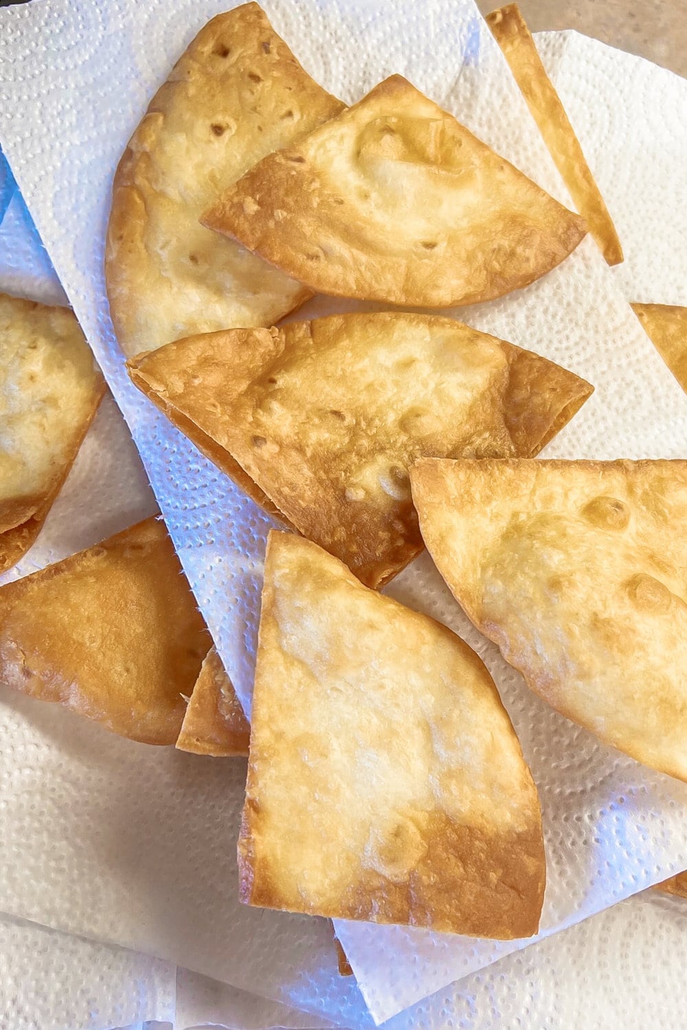 Fried flour tortilla triangles draining on paper towels. 