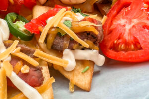 Beef Sizzle Steak Nachos with sour cream and sliced tomatoes.