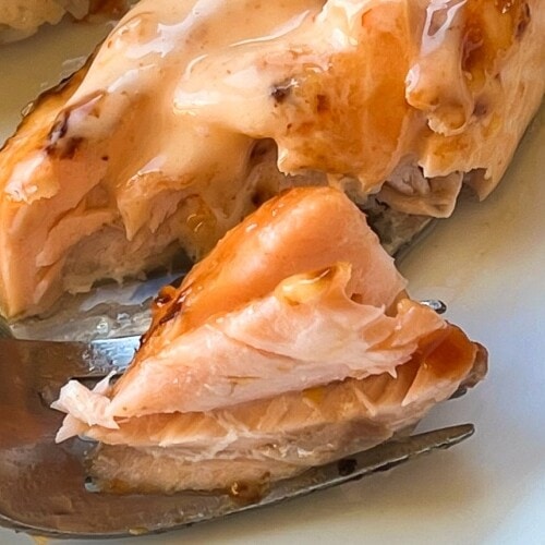 A large bite of salmon resting on a fork.