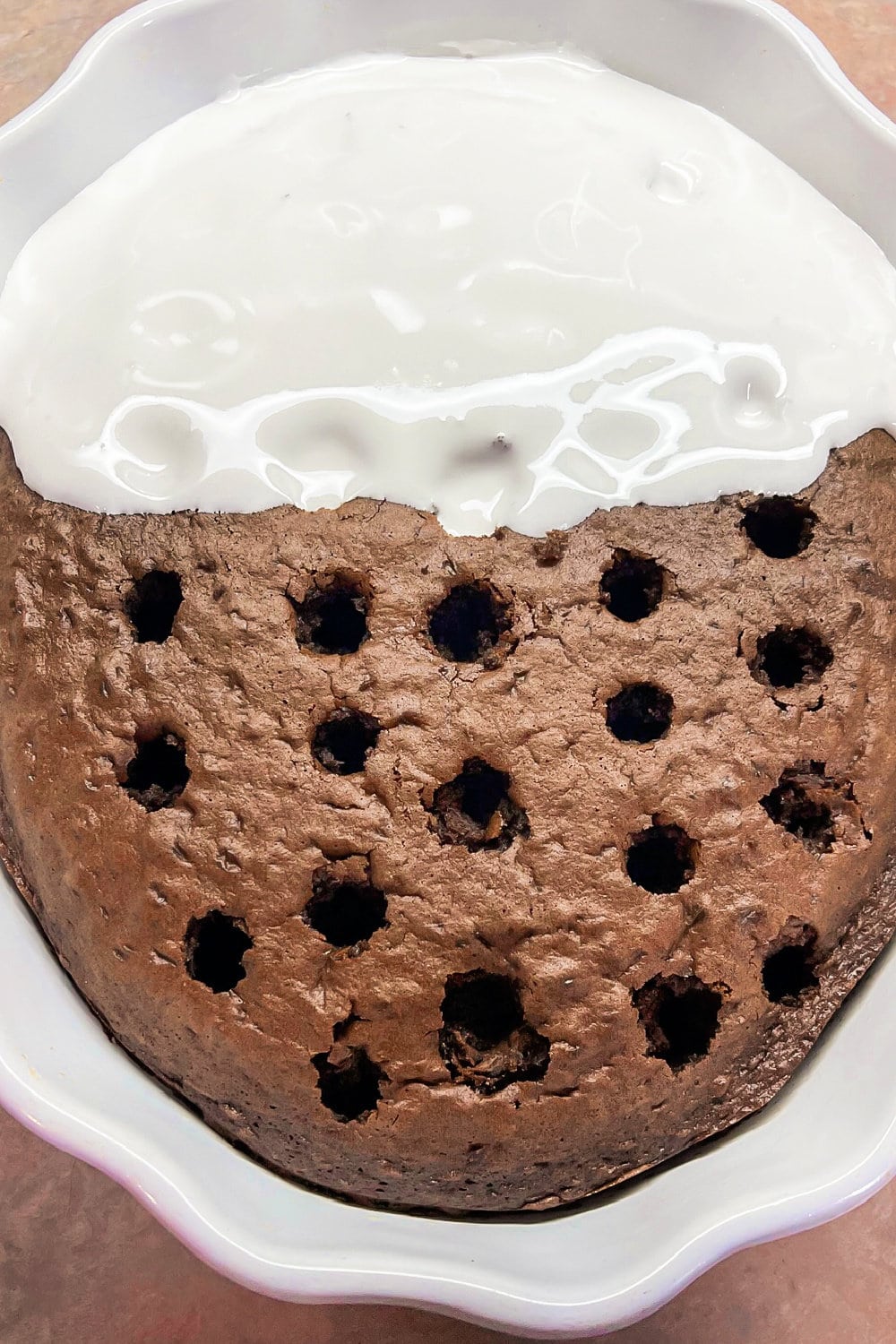 Chocolate cake with holes over the surface and marshmallow fluff. 