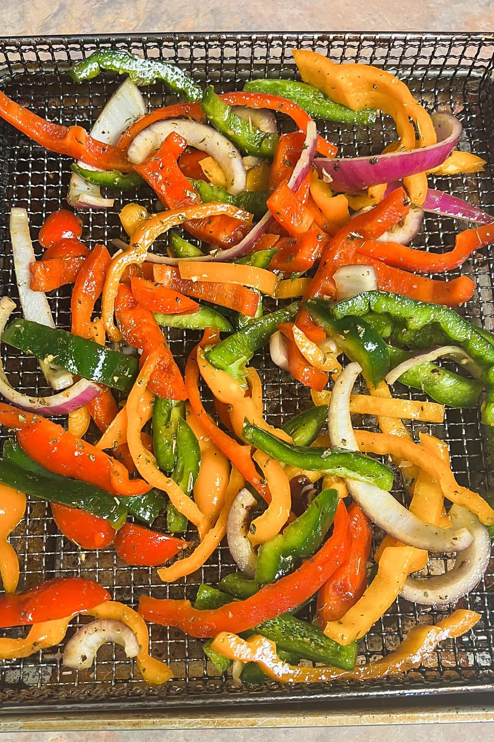 Sauteed air fryer purple onions and sweet bell peppers on a rack. 