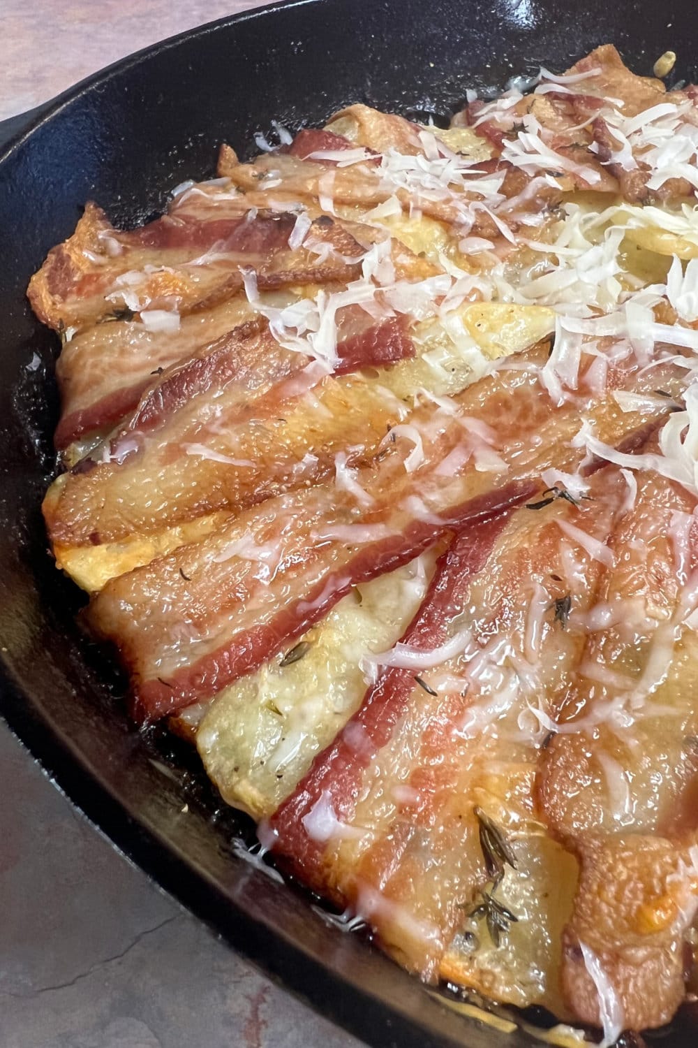 Crispy bacon on top of a bed of sliced potatoes with thyme. 