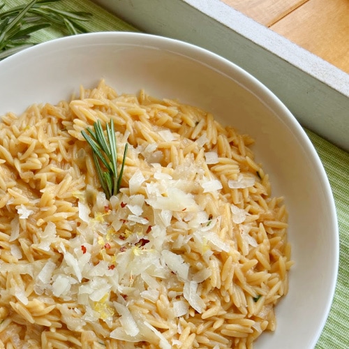 A bowl of Creamy Orzo Pasta with a garnish of rosemary.