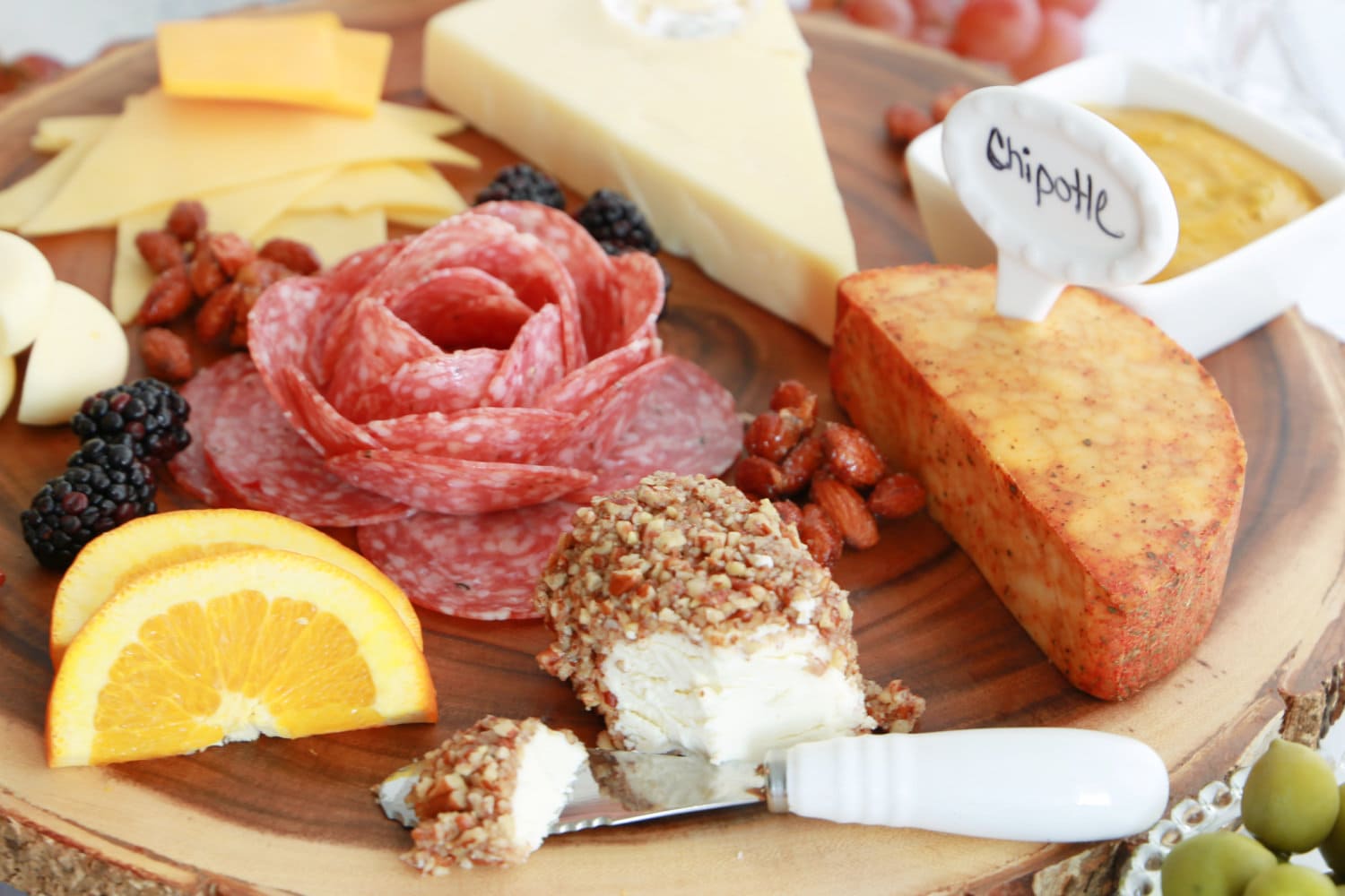 A charcuterie board featuring Honey Pecan Goat Cheese Rolls. 