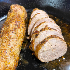 Sliced pork tenderloin in a skillet.