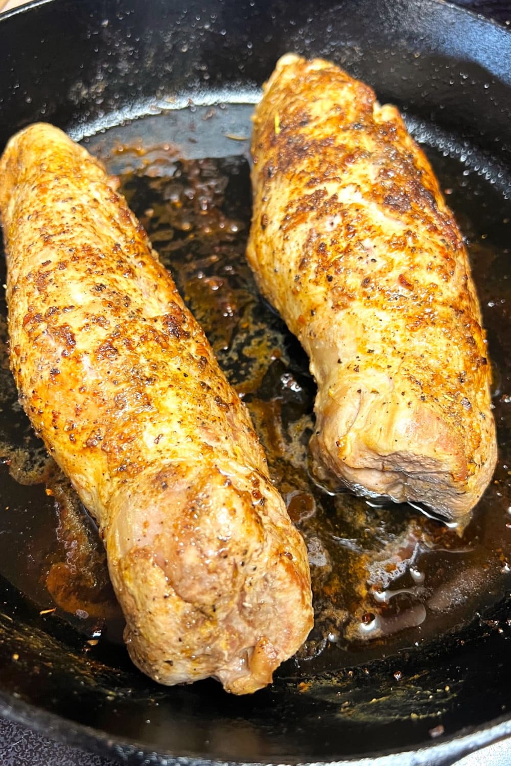 Pan-seared pork tenderloins in a skillet. 