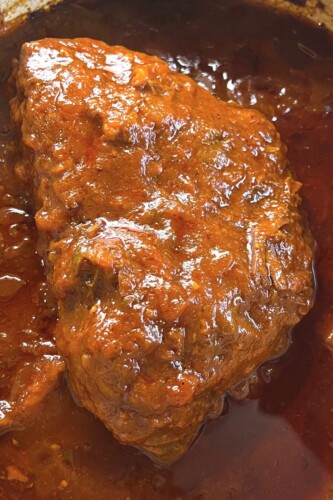 Bottom round rump roast in pot of tomato gravy. 