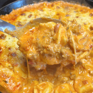 A big spoonful of creamy baked tortellini with meat sauce.