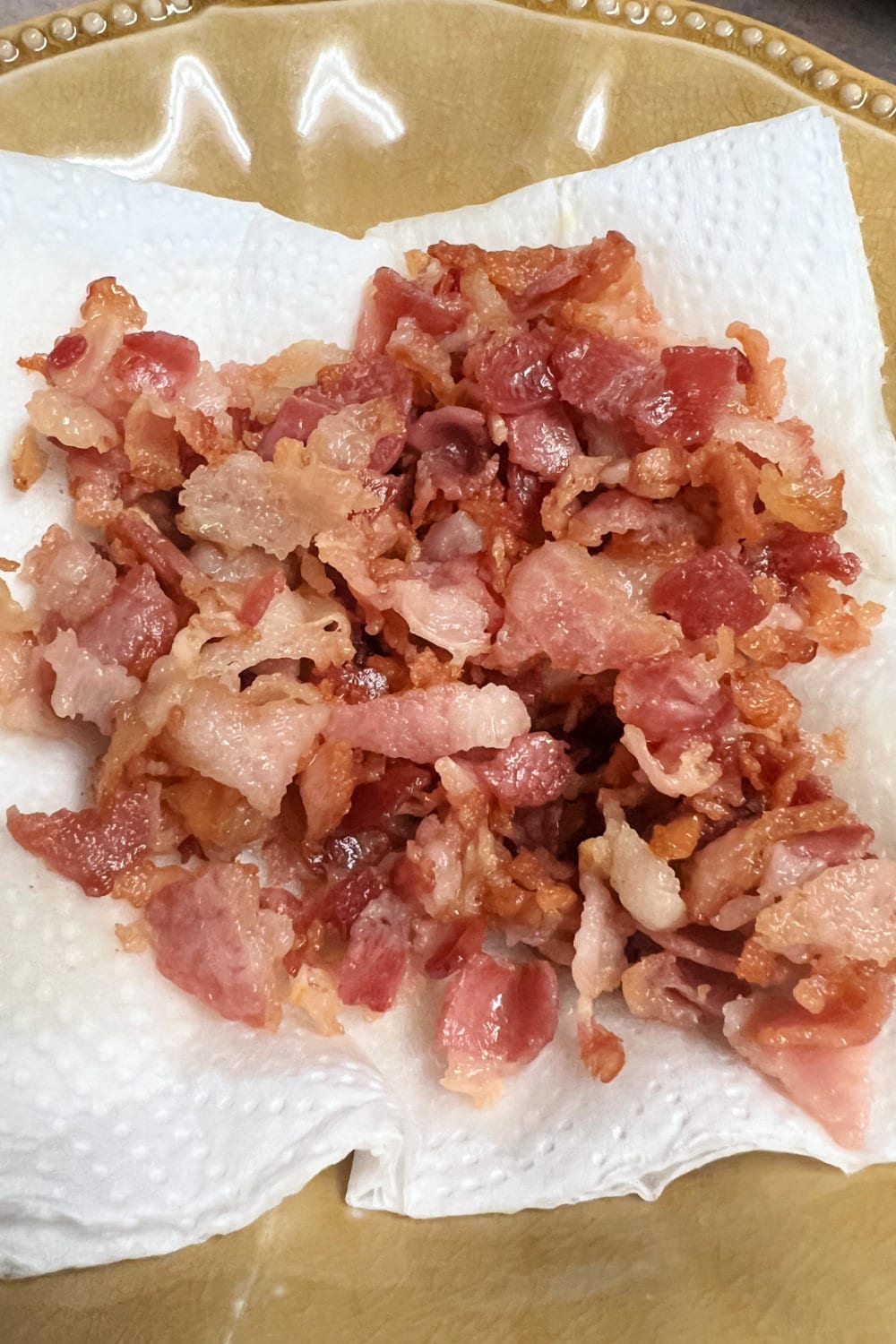 Cooked and crumbled bacon draining on paper towels. 