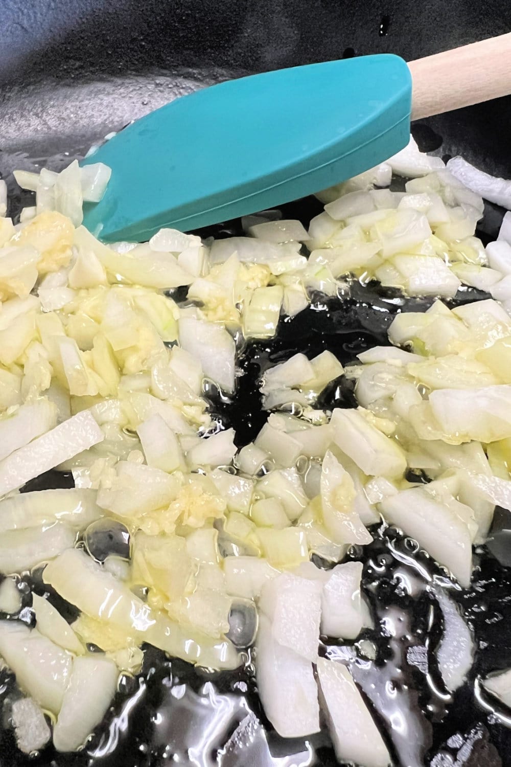 Chopped onions and minced garlic cooking in a skillet. 