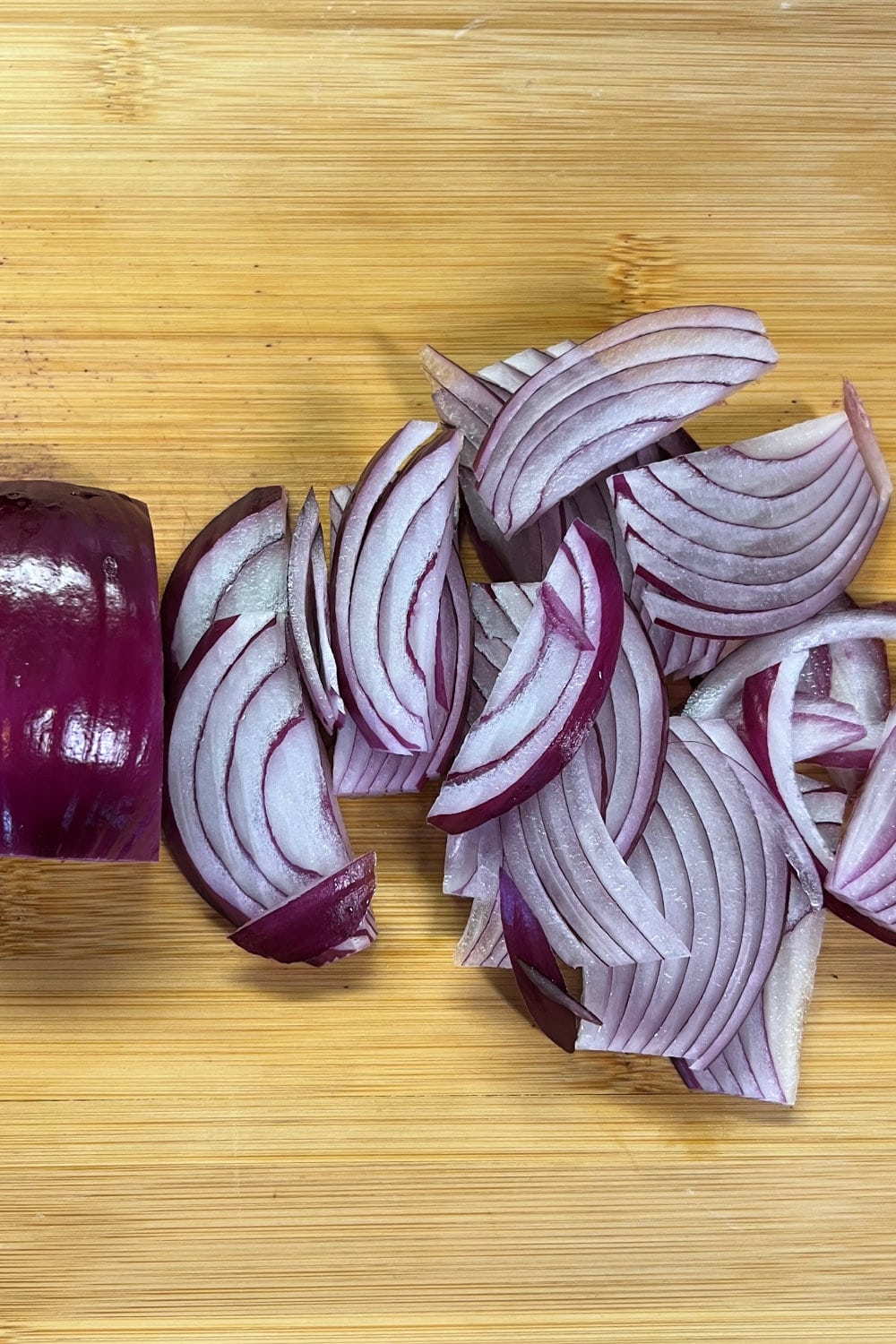 Thinly sliced red onion on a cutting board. 