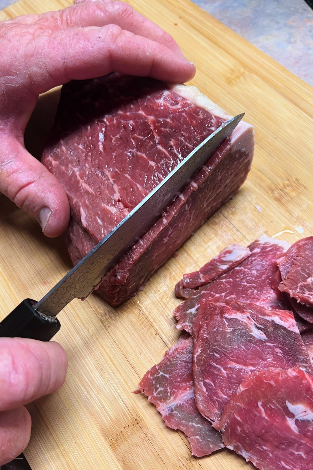 Slicing bottom round roast into 1/4-inch thick slices. 