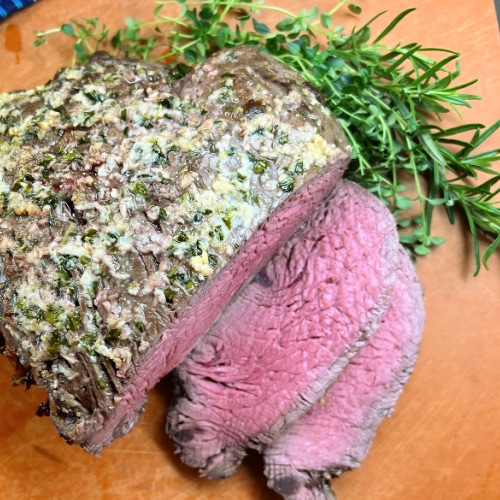 A whole beef tenderloin with slices next to it.
