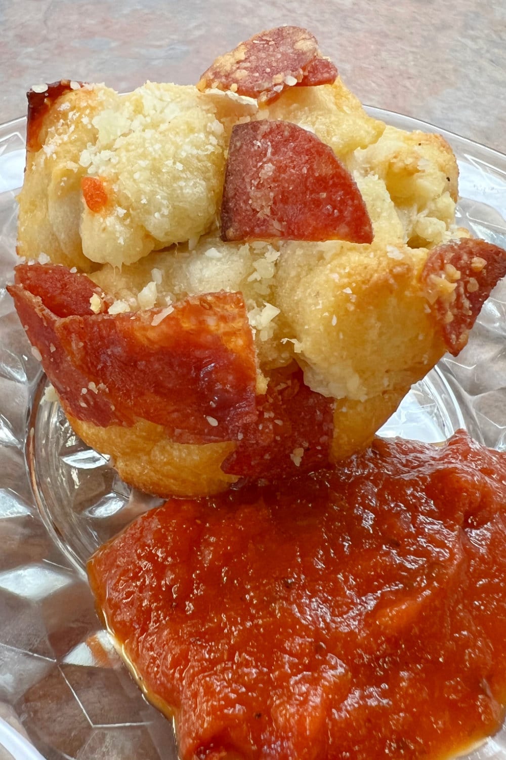 A bit fat Pepperoni Biscuit Bites on a plate with pizza sauce for dipping. 