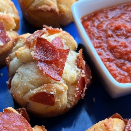 Pepperoni Biscuit Bites on a serving platter with pizza sauce on the side.