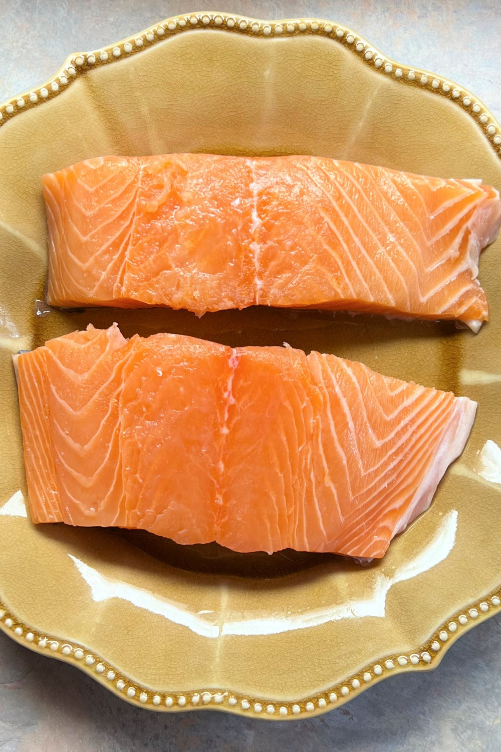 Two fresh salmon fillets on a plate. 