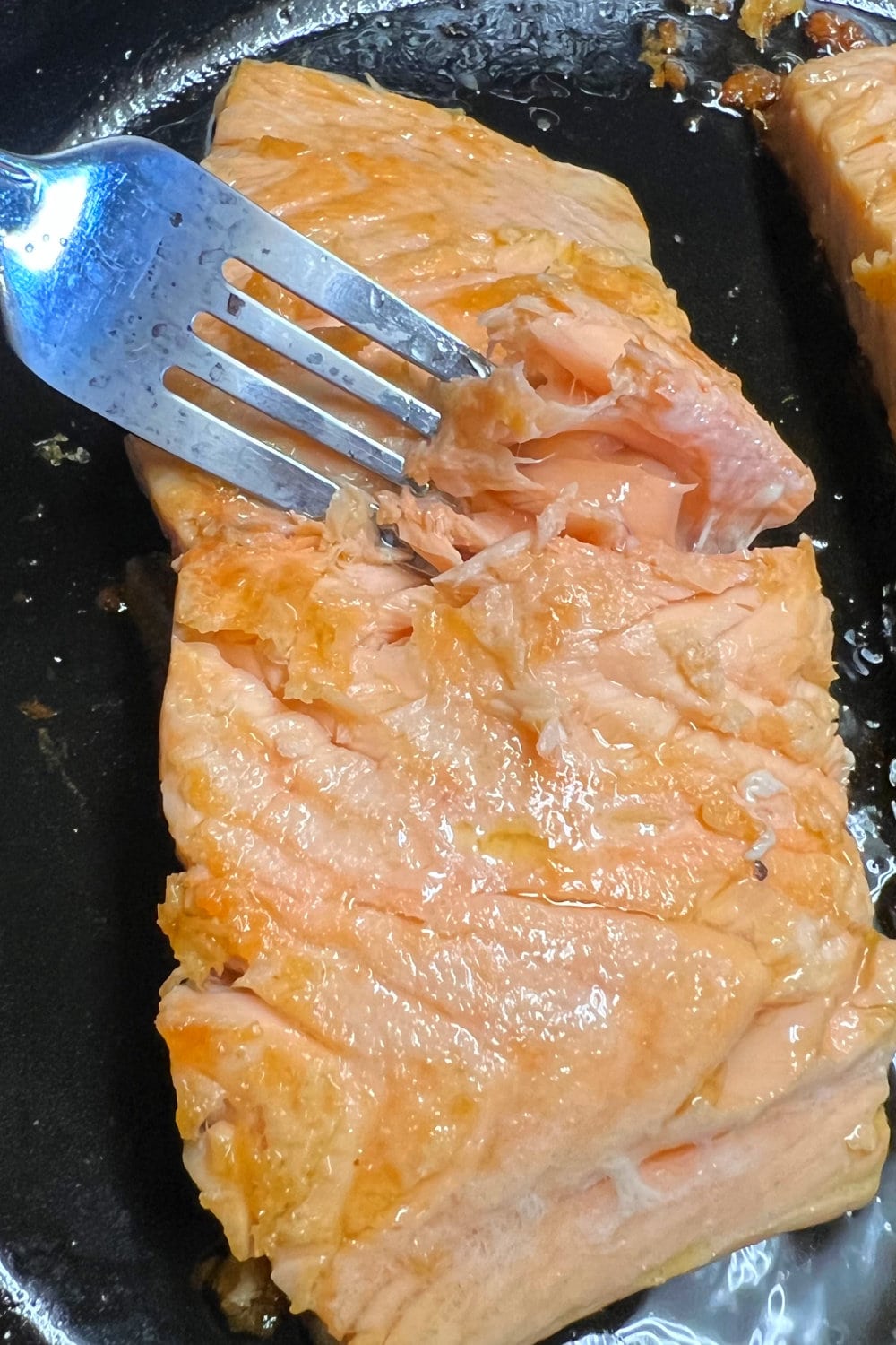 Testing a piece of salmon for doneness at the center with a fork. 