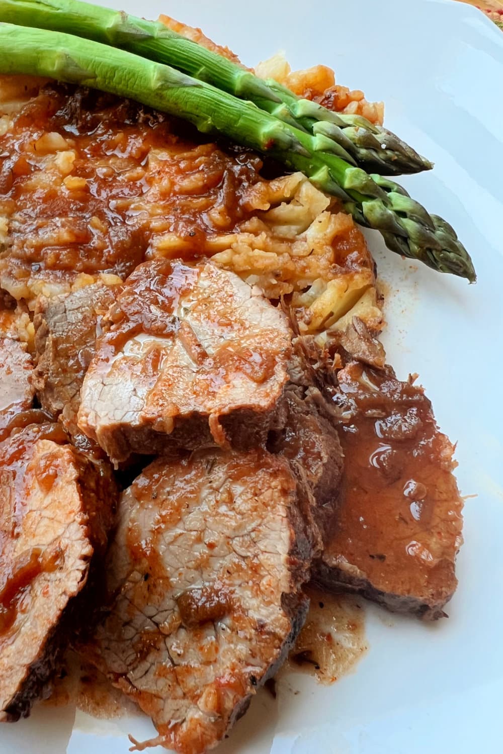 Instant Pot Rump Roast with potatoes, gravy and asparagus on the side.