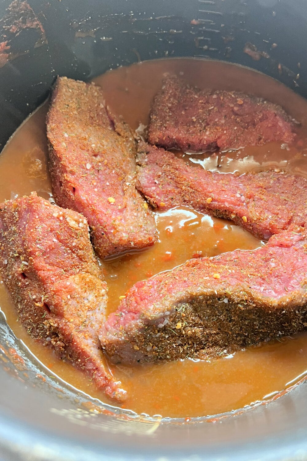 Seasoned beef placed into the cooking broth in the Instant Pot. 