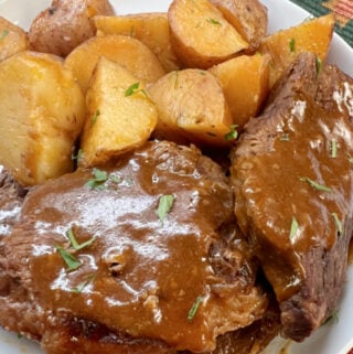 Rump roast with gravy and cooked potatoes on the side.