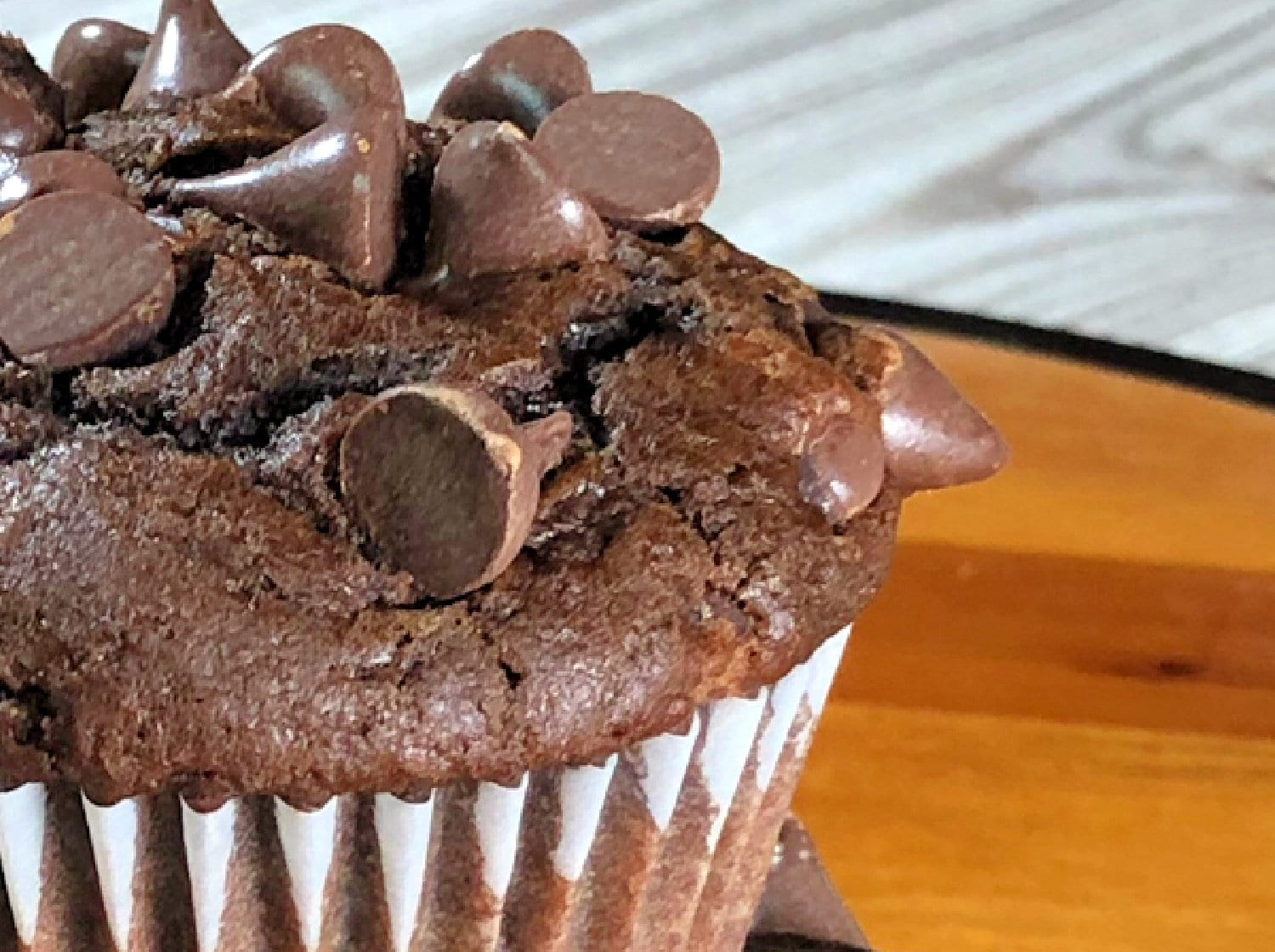 A moist apple sauce chocolate chip muffin in on a table. 