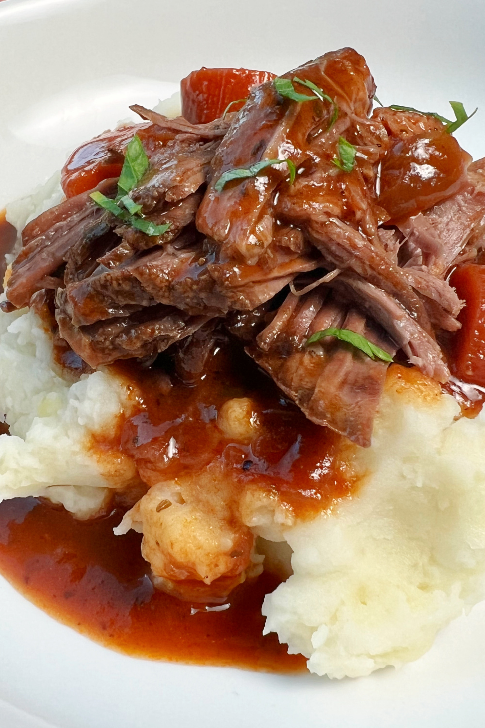 Shredded chuck tender roast with gravy on a bed of mashed potatoes. 