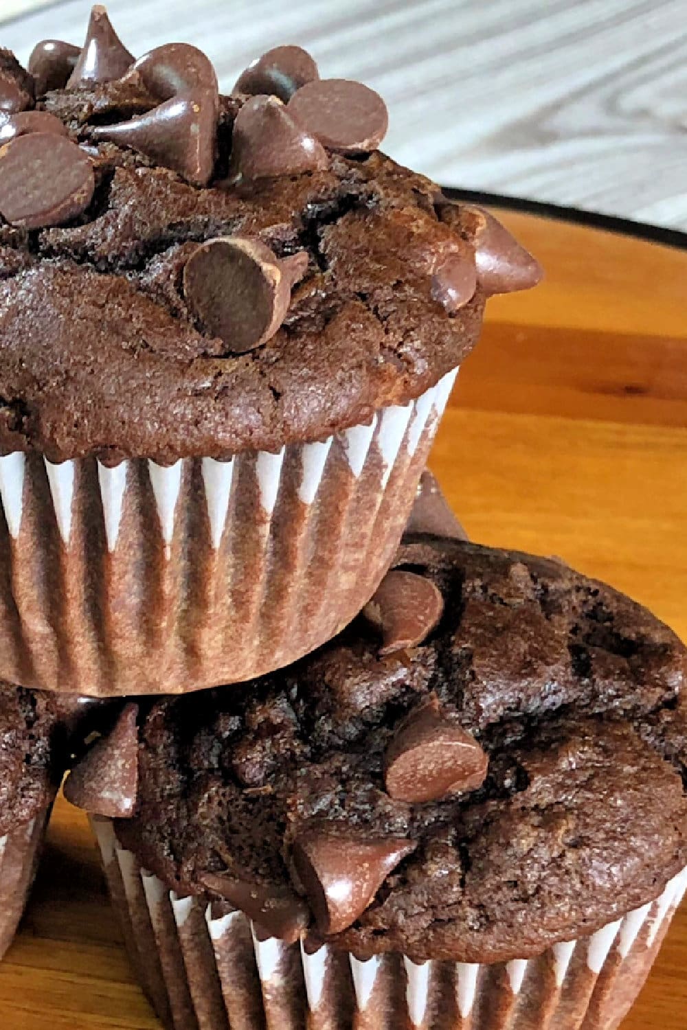 Stacked muffins in muffin cups that are chocolate chocolate chip.