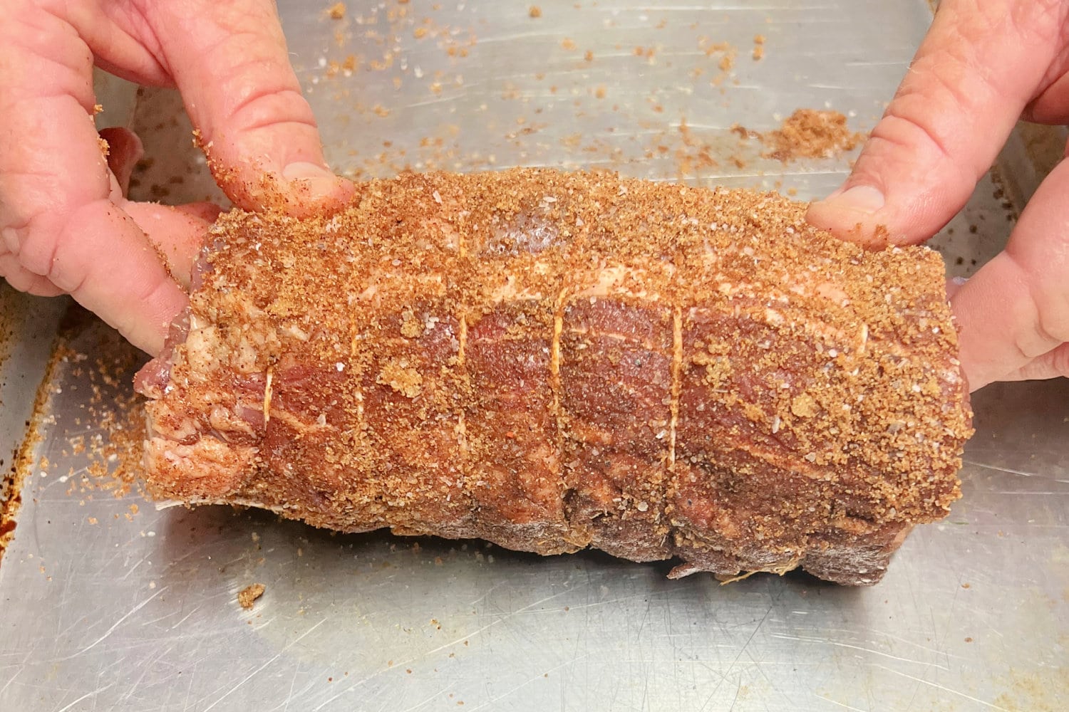 Dry rub pressed onto a tied beef tenderloin. 