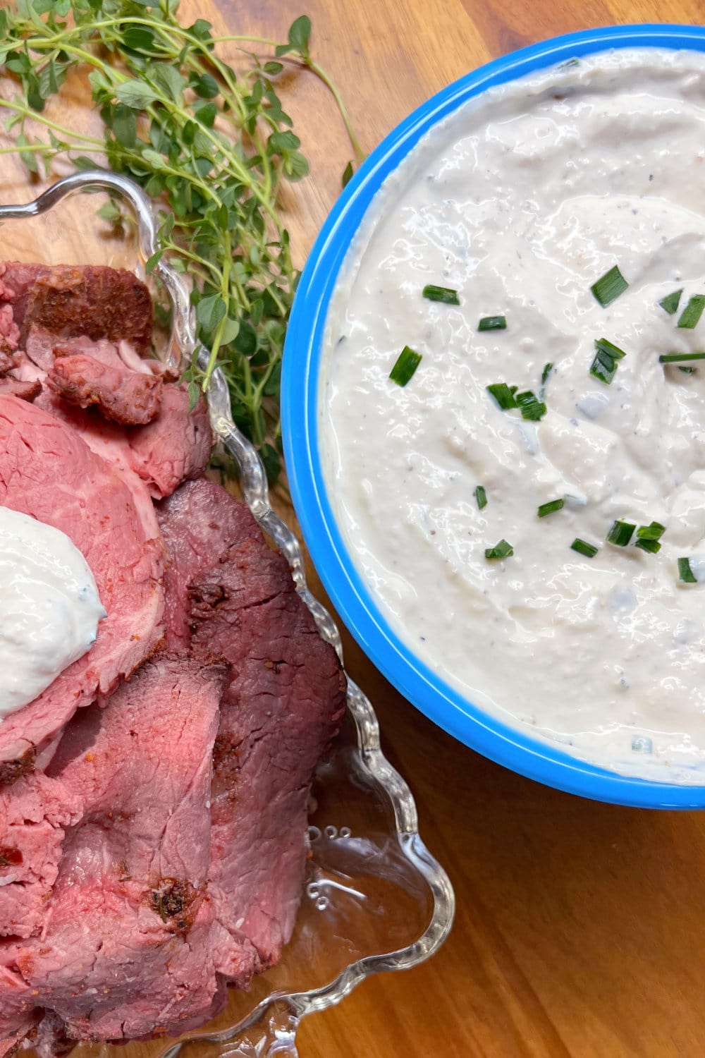 Medium-rare beef tenderloin slices next to a bowl of creamy horseradish sauce. 