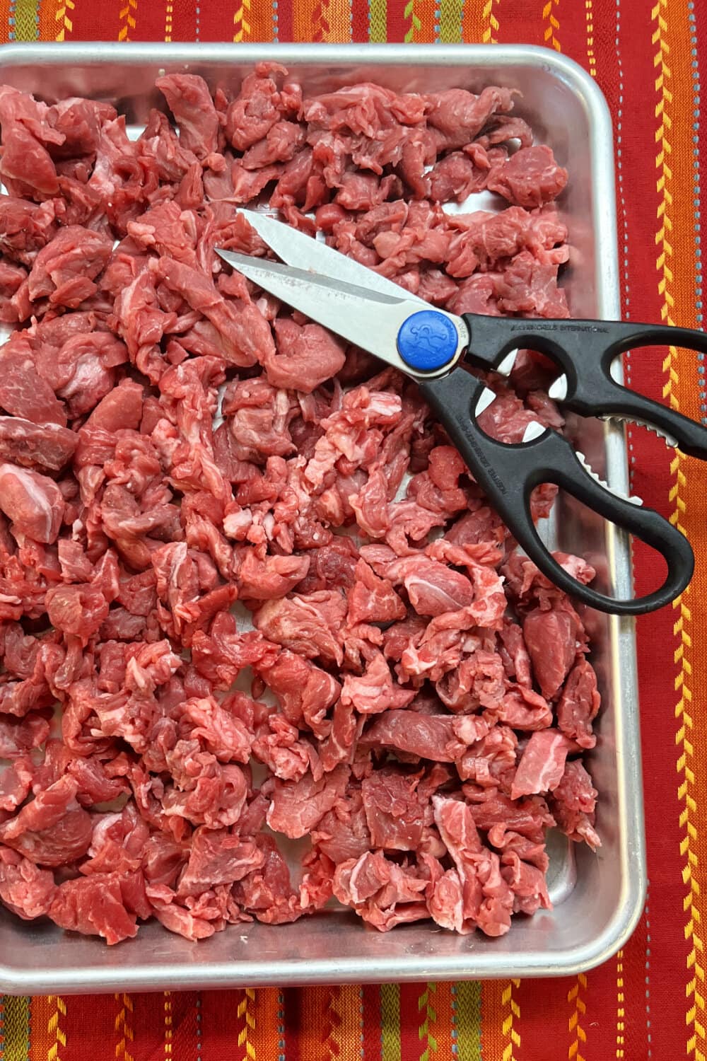 Minced beef on a baking sheet with kitchen shears. 