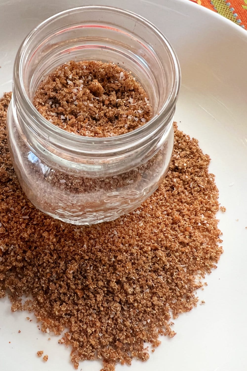 A jar of beef tenderloin rub resting in a mound of the same rub.