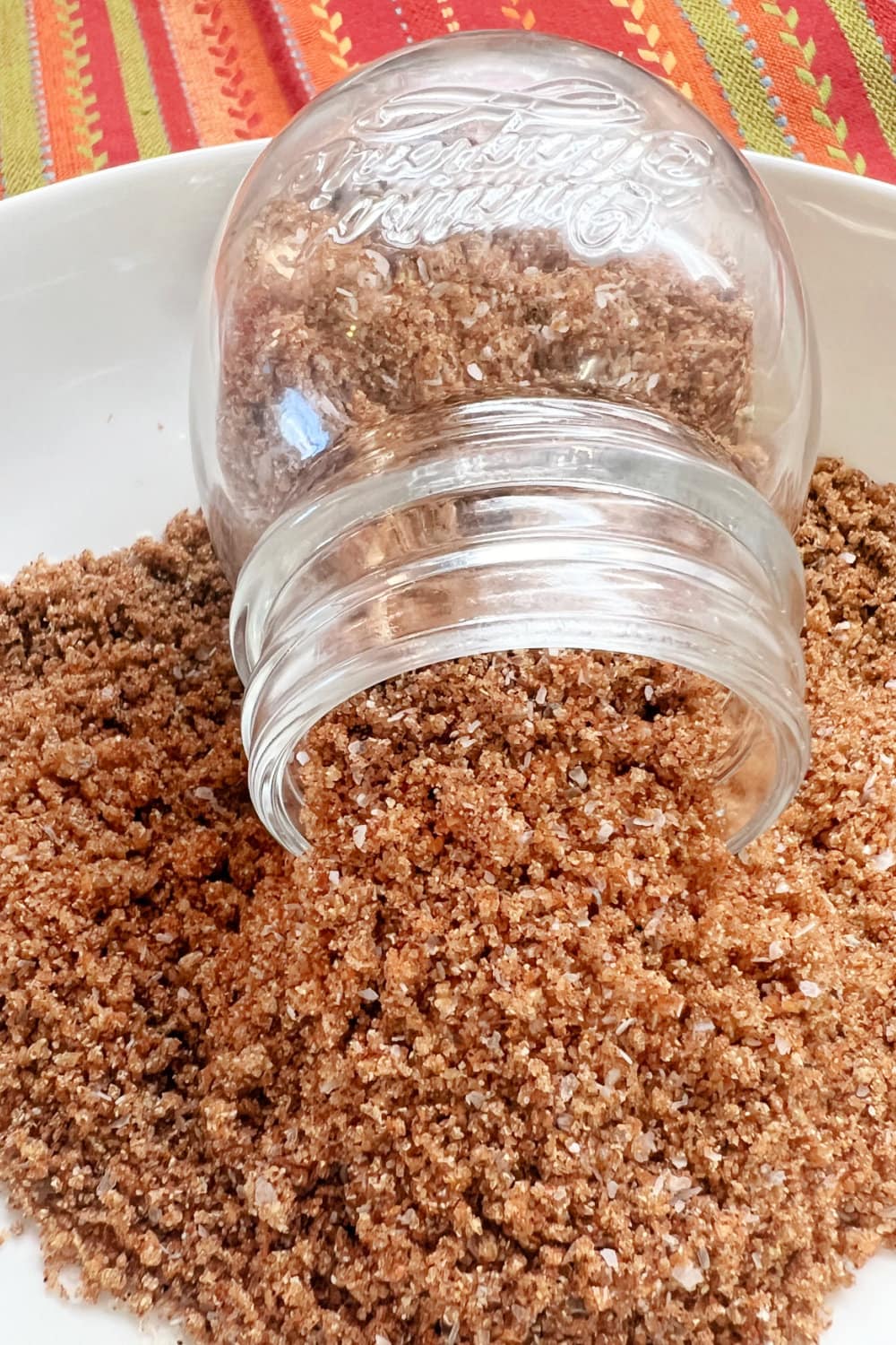 A tipped jar in a bowl of beef tenderloin spice rub. 