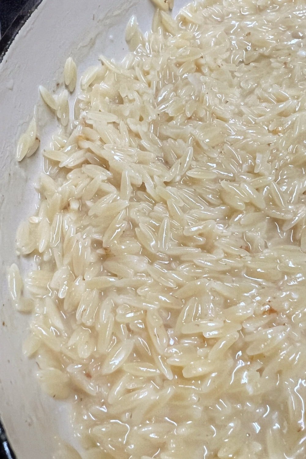 Orzo in a skillet, not quite fully cooked. 