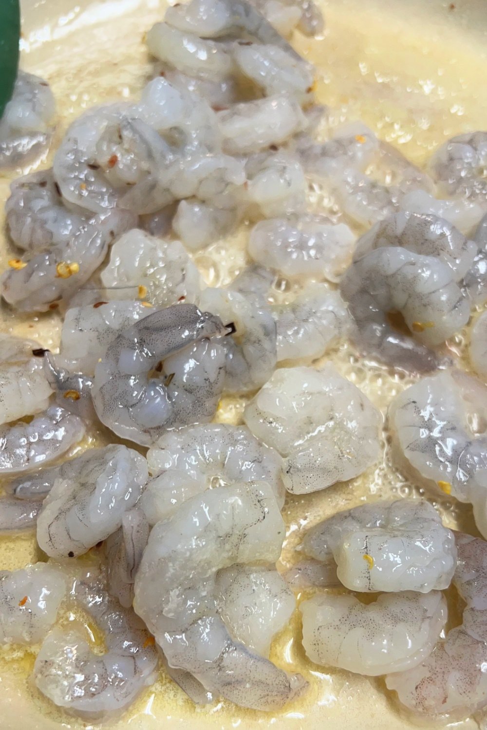 Raw shrimp in a skillet of hot butter. 