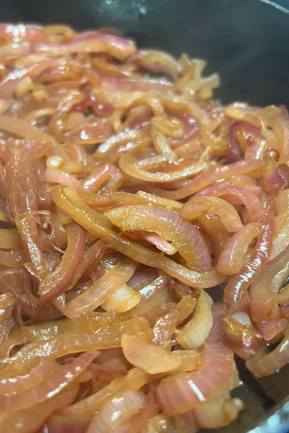 Caramelized sliced red onions in a skillet. 