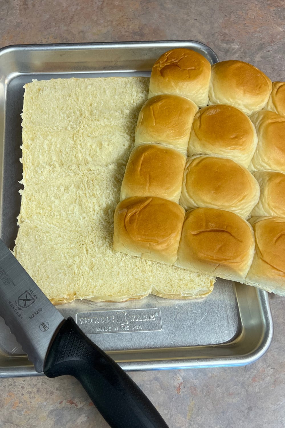 A sheet of slider buns cut in half horizontally to make a bottom and a top. 