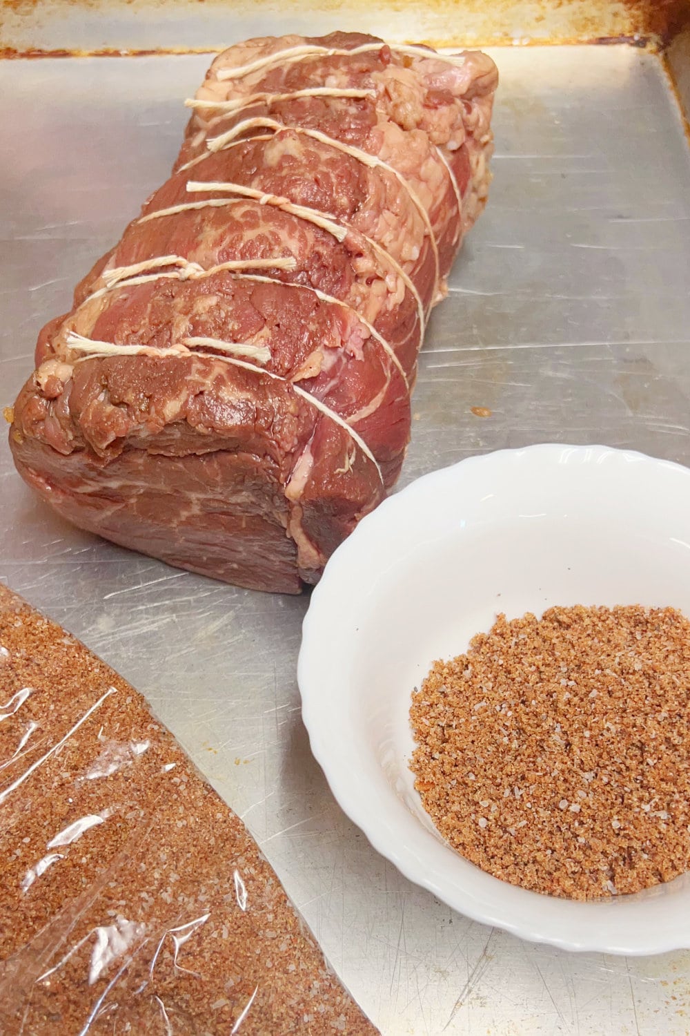 Beef tenderloin tied with string, ready to be massaged with spice rub.