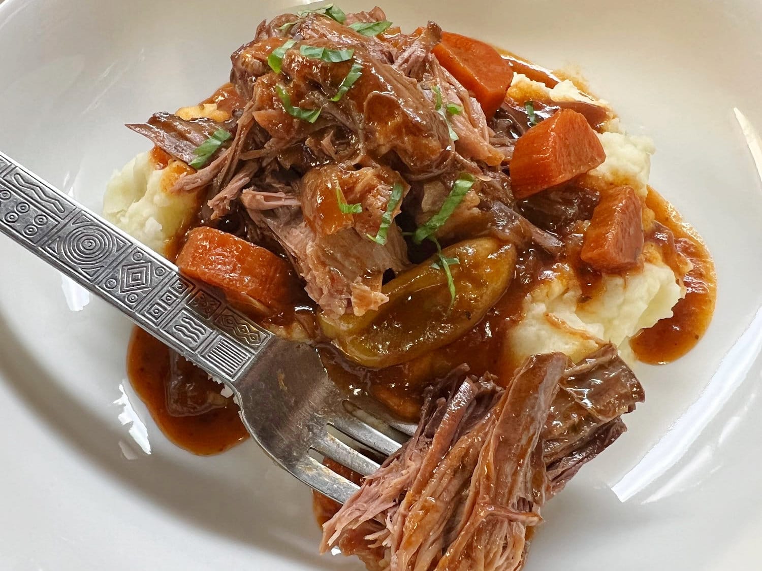 Chuck tender roast served with carrots, mashed potatoes, and gravy. 