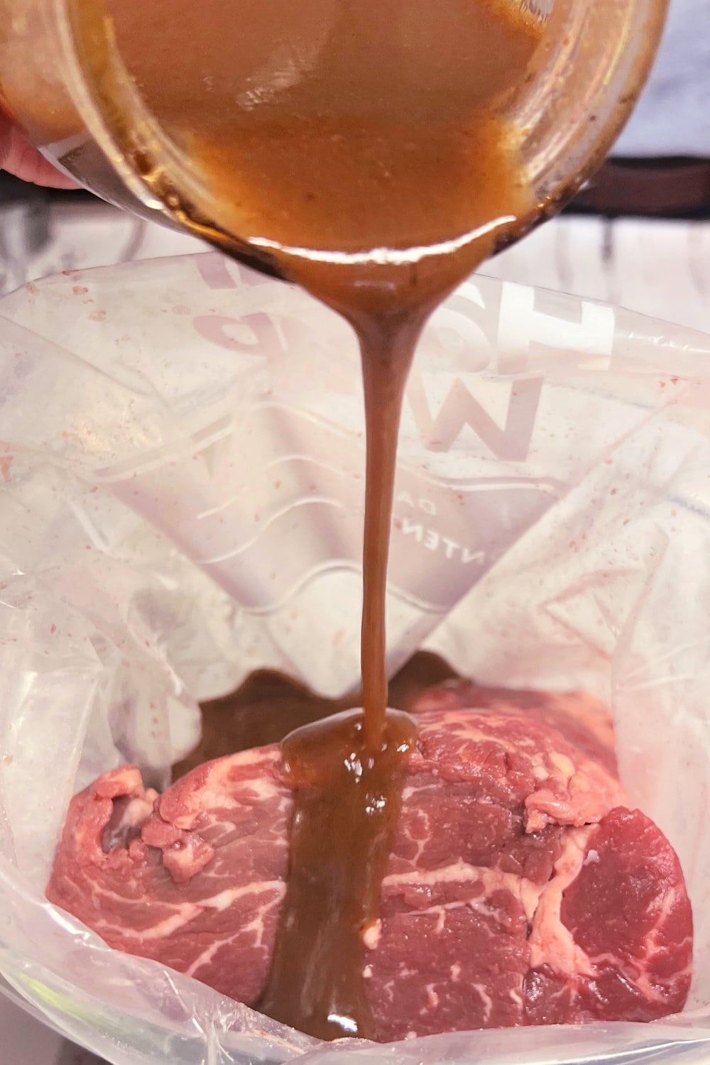 Pouring marinade over beef tenderloin in a bag. 