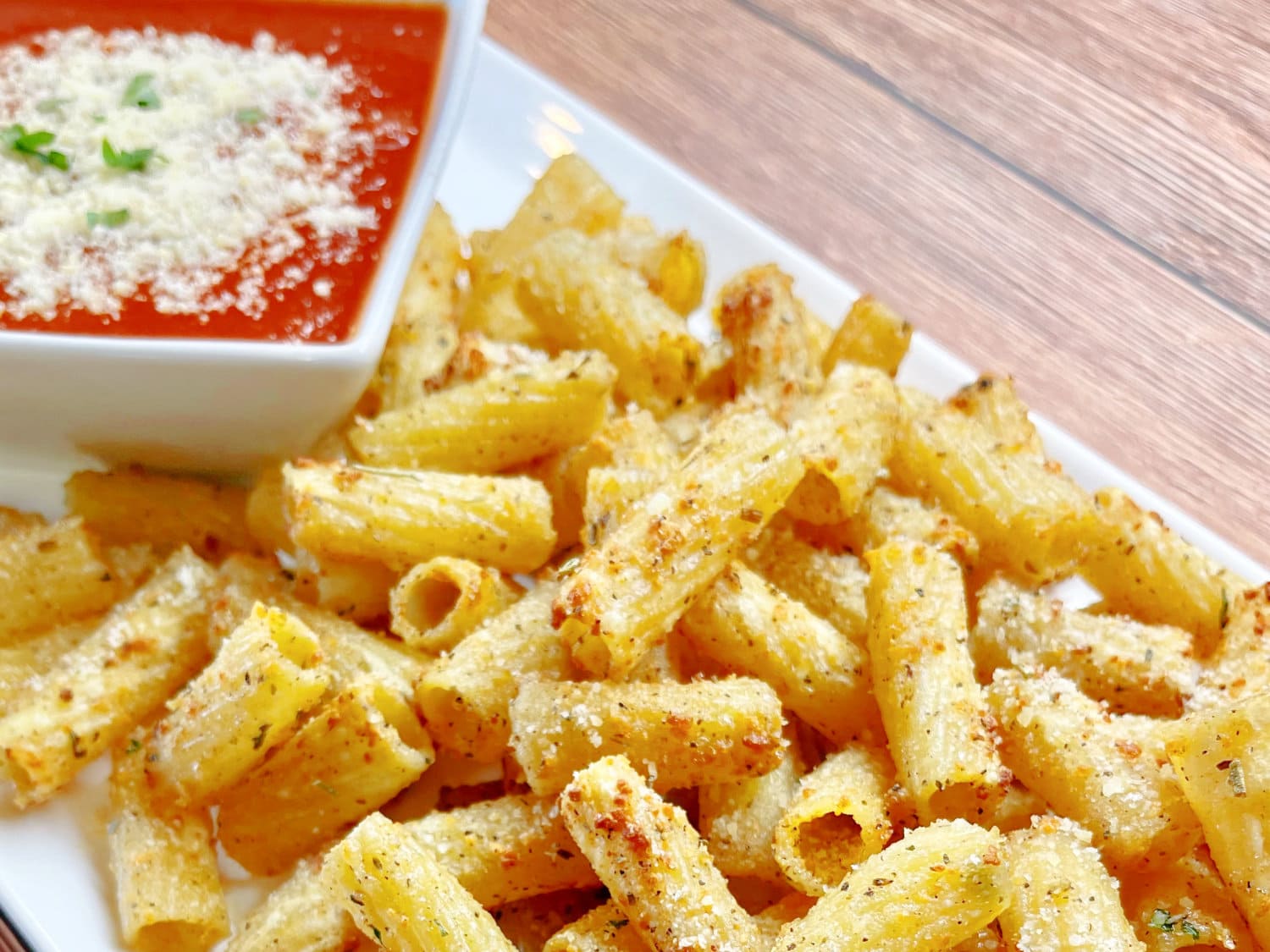Hot and ready, a pile of air fryer pasta chips on a white platter. 