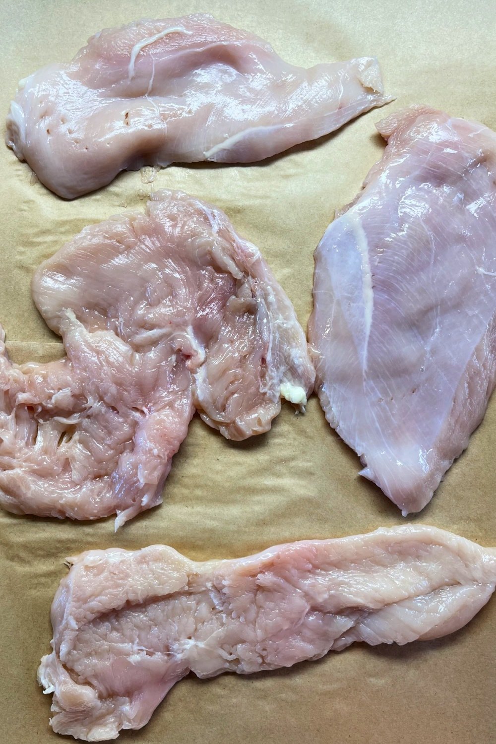 Chicken cutlets pounded out to 1/4-inch thickness on parchment. 