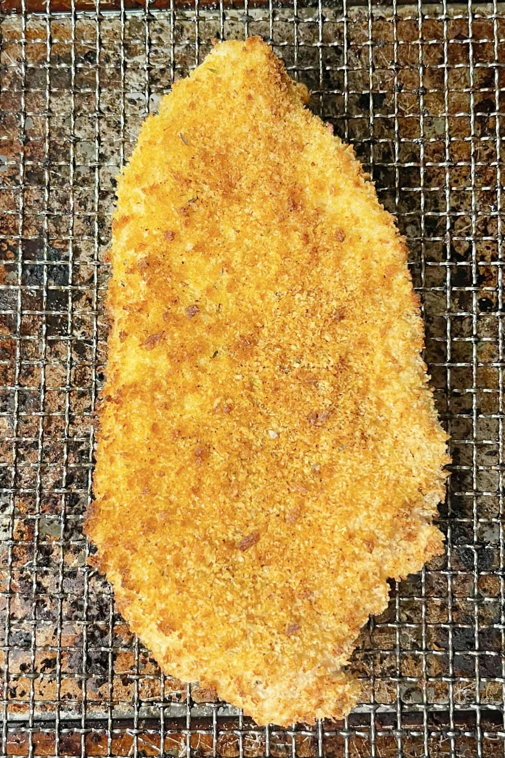 Crispy and golden brown chicken cutlet on an air fryer rack. 
