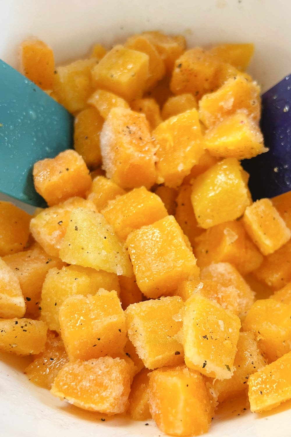 Cubes of seasoned butternut squash in a white bowl. 