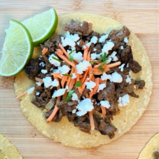 Carne Picada Taco with sliced limes on the side.